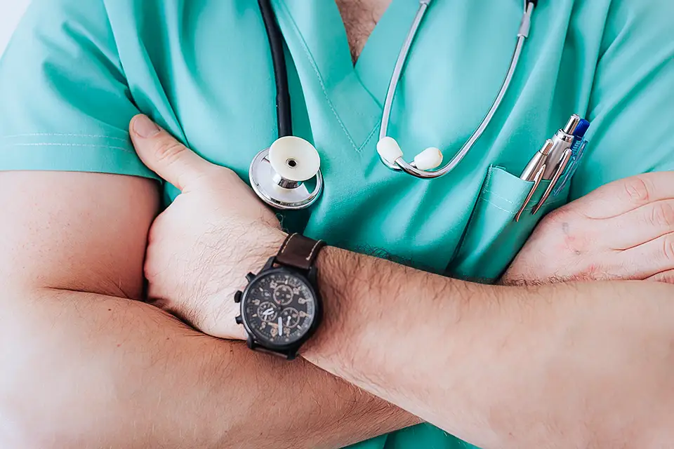 Male doctor in scrubs crossing his arms over his chest.