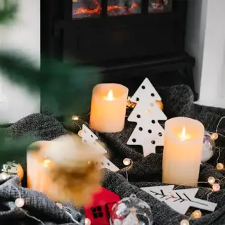 A warm holiday scene with candles, toys and a fireplace in the background.