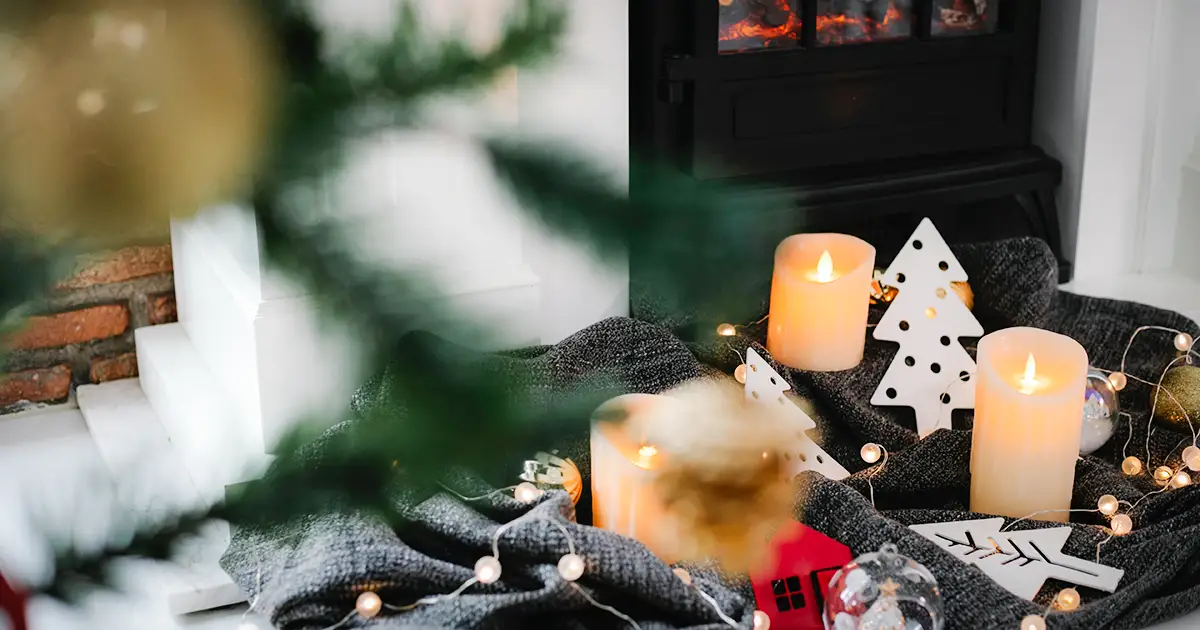 A warm holiday scene with candles, toys and a fireplace in the background.