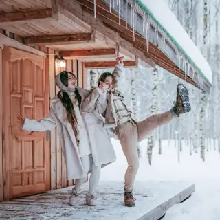 Couple laughing together as they stand on an icy porch in the middle of winter.