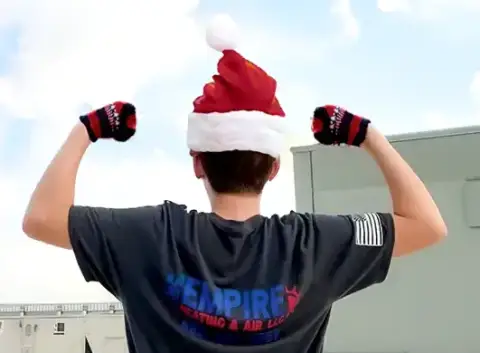 An Empire Heating & Air technician in a santa hat and gloves
