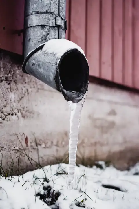 Water frozen to ice in a winter downspout