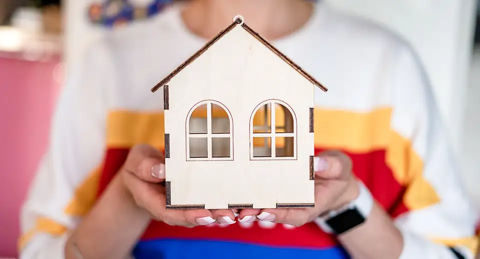 A woman holds a model of a house